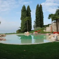 Elegant inground pool with natural rock features and surrounding greenery in Long Island, NY. Luxury inground pool with natural rocks and lush landscaping in Long Island.