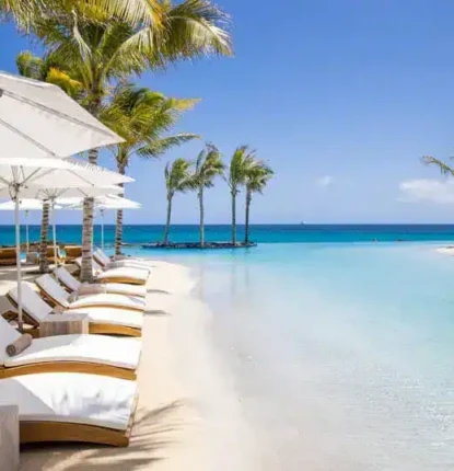 Elegant outdoor pool area with loungers, umbrellas, and palm trees overlooking the ocean. Luxury poolside scene with loungers, umbrellas, and palm trees by the ocean.