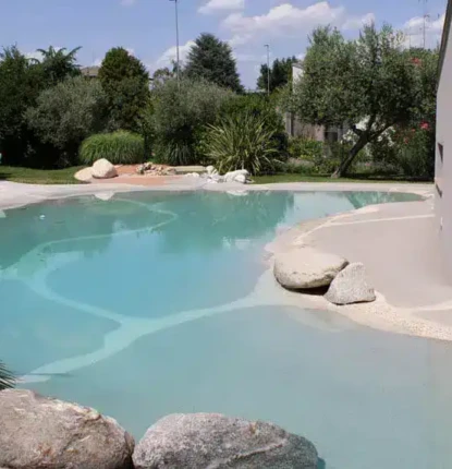 Inground pool with surrounding outdoor furnishings and lush landscape.