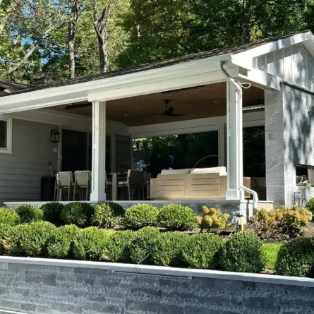 Elegant outdoor living area with a covered roof, seating, and fireplace in Roslyn, Long Island. Covered outdoor patio with seating and fireplace in Roslyn.