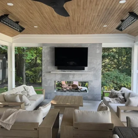 Elegant outdoor living space with a TV, cozy seating, and a wooden ceiling, perfect for relaxing or entertaining. Covered outdoor living area with comfortable seating and a TV.