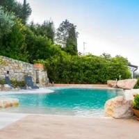 Elegant inground pool with outdoor seating and lush greenery in Long Island, perfect for outdoor living. Beautiful inground pool with outdoor furnishings in Long Island setting.