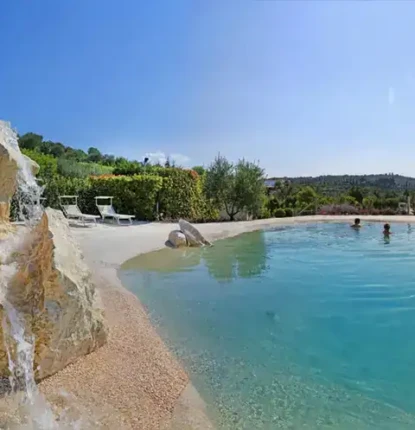 Luxury outdoor pool with rock waterfall and scenic landscape.
