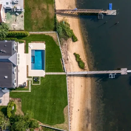 Aerial view of a Long Island backyard with inground pool and waterfront dock.