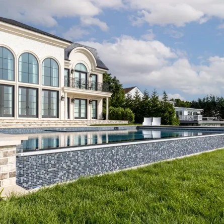 Elegant inground pool with modern outdoor furnishings in a luxurious backyard.