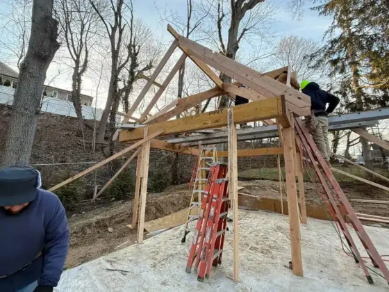 Construction workers building a wooden pool structure in a backyard.
