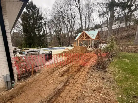 Construction site with dirt mound and pool area in Long Island.