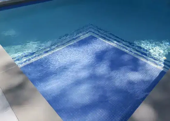 Inground pool with blue tiles and clear water in Long Island.