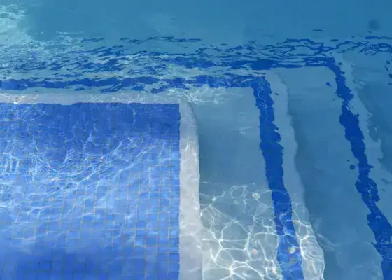 Inground pool with blue tiles and clear water on Long Island.
