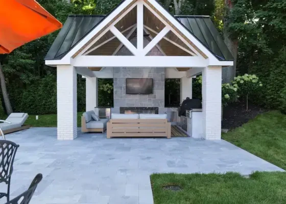 Beautiful outdoor patio with fire pit, seating, and a small structure in a lush backyard.