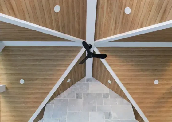 Interior ceiling with wooden panels and white beams in modern style.
