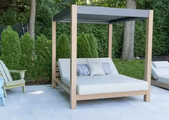 Elegant outdoor daybed with canopy and pillows in lush garden setting.