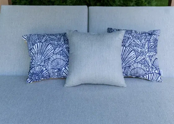 Poolside outdoor cushions with blue shell pattern pillows and a neutral central pillow.