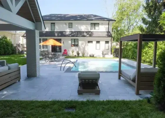 Beautiful backyard with inground pool, outdoor furniture, and lush greenery.