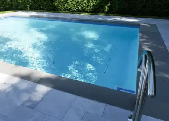 Beautiful inground pool with clear blue water and modern poolside area.