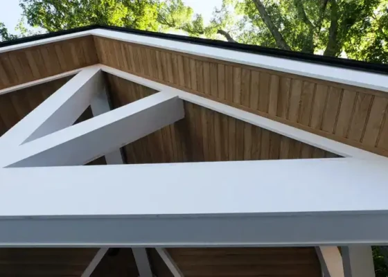 Contemporary house roof with wooden and white accents in a lush setting.