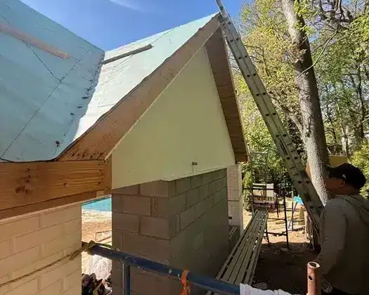 Construction of outdoor pool area with roofing and scaffolding in progress.