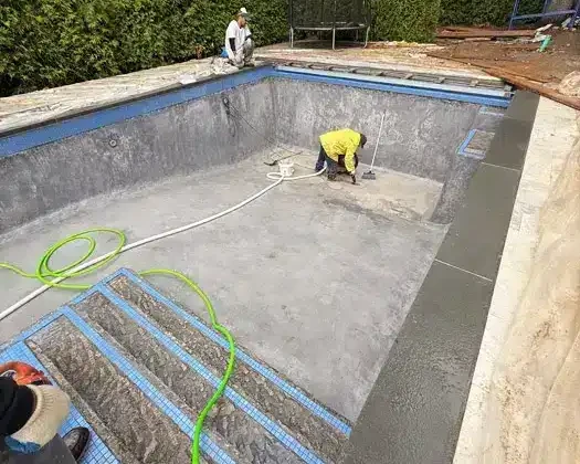 Inground pool construction with workers installing the pool shell.