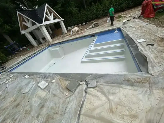 New inground pool under construction with steps and surrounding area.