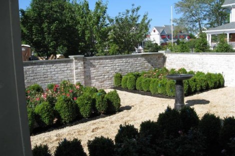 A landscaped residential yard featuring bushes, trees, and a birdbath, showcasing outdoor design and gardening skills. Well-maintained garden with bushes, trees, and a birdbath in a residential yard.