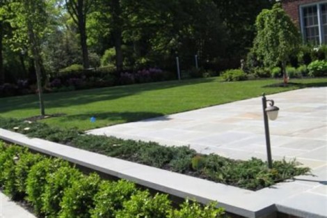Elegant backyard landscaping featuring a spacious patio, lush greenery, and outdoor lighting for outdoor living. Beautiful landscaped backyard with patio, greenery, and outdoor lighting on Long Island.