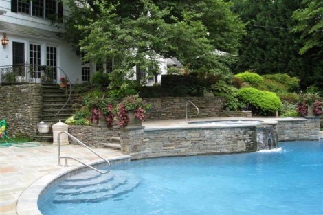 Elegant inground pool surrounded by greenery and outdoor furniture, perfect for outdoor living in Long Island. Beautiful inground pool with lush landscaping and outdoor furnishings in Long Island.