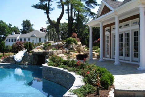Elegant backyard with inground pool, lush landscaping, and outdoor furnishings in Long Island. Beautiful inground pool with outdoor furnishings in a landscaped backyard.