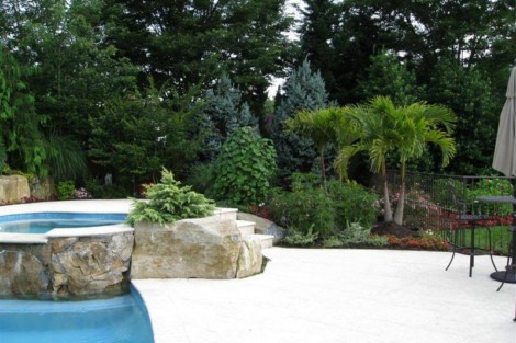 Elegant backyard featuring a pool, hot tub, lush landscaping, and outdoor furniture in Long Island. Luxury backyard with pool, hot tub, and outdoor furnishings in Long Island.