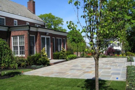Elegant backyard landscaping featuring a paved patio, trees, and well-maintained lawn in Long Island. Beautiful backyard with paved patio and lush greenery in Long Island.