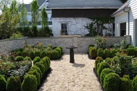 A neatly landscaped garden featuring trimmed bushes and a central bird bath, perfect for outdoor relaxation. Well-maintained garden with trimmed bushes and a bird bath in the center.