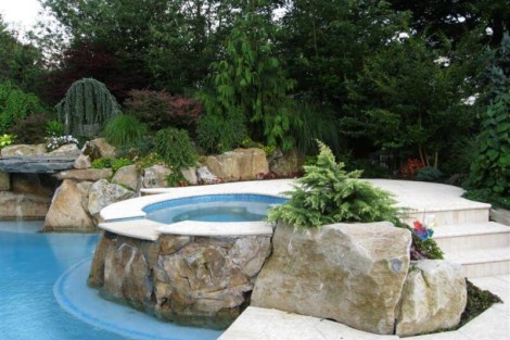 Elegant backyard with inground pool, natural rocks, and vibrant landscaping for outdoor relaxation. Beautiful backyard with inground pool, rocks, and lush landscaping in Long Island.