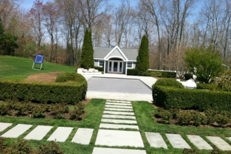 Well-designed garden with stone pathway, lush bushes, and trees, perfect for outdoor relaxation and entertaining. Landscaped garden with pathway, bushes, and trees in a backyard setting.