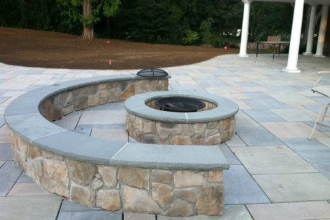 Beautiful stone fire pit with curved seating area, perfect for outdoor gatherings and relaxation. Stone fire pit with curved seating on a paved patio.