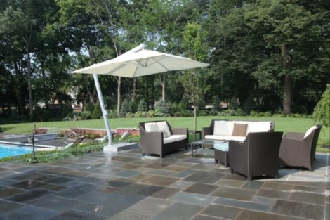 Elegant outdoor living area with seating, umbrella, and pool, perfect for relaxing and entertaining in Long Island. Outdoor patio with furniture, umbrella, and pool in Long Island.