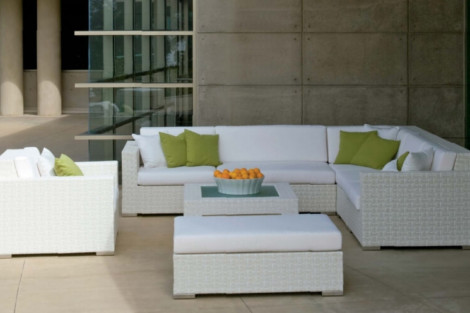 Stylish outdoor lounge setup with white wicker furniture and vibrant green cushions, perfect for outdoor living. Contemporary outdoor sectional sofa with green cushions and matching ottoman.