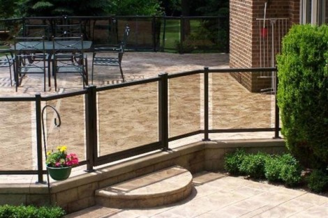 Elegant outdoor patio with pool fencing, seating area, and lush greenery in Long Island. Long Island pool fencing with black metal railing and outdoor patio area.