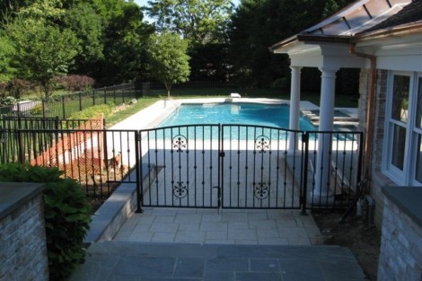 Beautiful inground pool with fencing and outdoor furniture, perfect for outdoor living on Long Island. Inground pool with black fence and outdoor furnishings on Long Island.