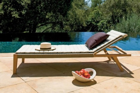 Relaxing outdoor poolside lounge chair with pillows, hat, and a bowl of fruit for outdoor living enjoyment. Poolside lounge chair with hat and pillows by the pool.
