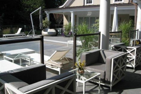 Stylish outdoor patio with comfortable seating, lush plants, and a view of the house, perfect for outdoor gatherings. Elegant outdoor patio with seating and lush greenery in Long Island.