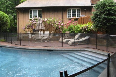 Beautiful inground pool with fencing, outdoor furniture, and lush landscaping in Long Island. Inground pool with safety fencing and outdoor seating area in Long Island.