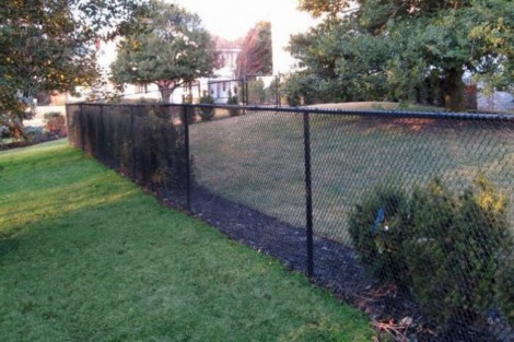 Durable black chain-link fence installed by All Island Group in Long Island for privacy and security. Black chain-link fence installed around a grassy yard in Long Island.