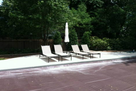 Relaxing outdoor pool area with lounge chairs and umbrella, perfect for outdoor living in Long Island. Outdoor pool area with lounge chairs and umbrella in Long Island.