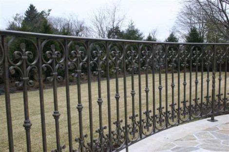 Custom wrought iron fence installed for privacy and aesthetic appeal in a backyard setting. Elegant wrought iron fence with intricate design for outdoor fencing.