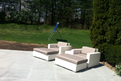 Comfortable outdoor lounge furniture set with beige cushions and a blue umbrella in a lush garden. Outdoor patio furniture with beige cushions and a blue umbrella in a garden setting.