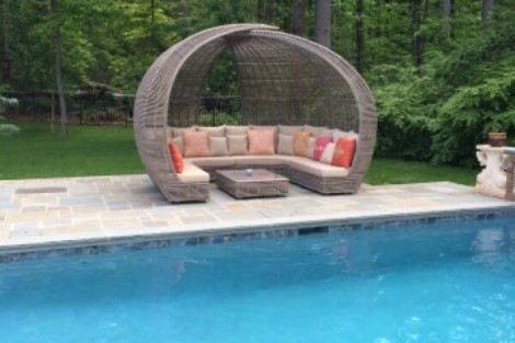 Luxurious poolside outdoor lounge with curved canopy and comfortable cushions, perfect for relaxing outdoors. Poolside outdoor lounge with curved canopy and cushioned seating.