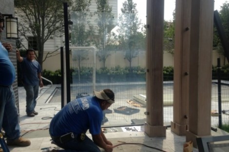 Workers installing pool fencing and outdoor furnishings at a Long Island property. Construction workers installing outdoor pool fencing and furnishings.