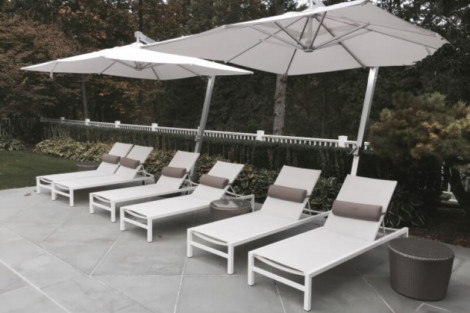 Comfortable outdoor lounge chairs with umbrellas and side tables for relaxing outdoor living. Outdoor lounge chairs with umbrellas and side tables on patio.