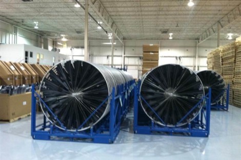 Solar panel rolls stored in a warehouse, ready for installation or distribution. Large black solar panel rolls stored in a warehouse with industrial shelving.