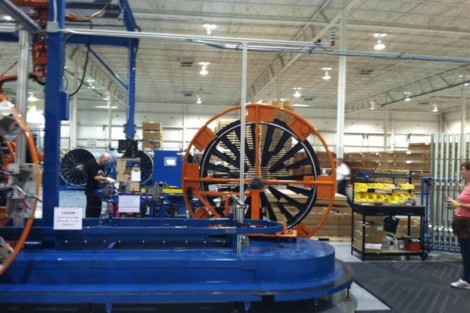 Workers operate large industrial machinery in a manufacturing facility, showcasing advanced production processes. Industrial machinery and workers in a manufacturing plant setting.