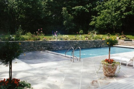 Elegant inground pool with outdoor seating and vibrant landscaping in Long Island. Beautiful inground pool with outdoor furniture and lush greenery.
